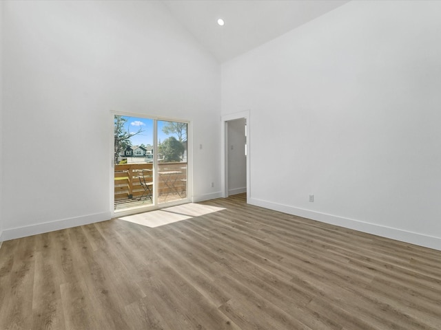 unfurnished room with wood finished floors, high vaulted ceiling, baseboards, and recessed lighting