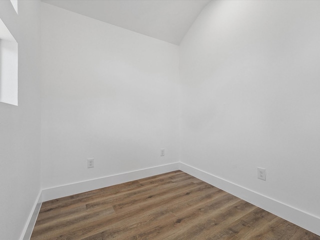 unfurnished room featuring lofted ceiling, baseboards, and wood finished floors