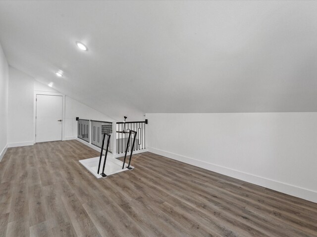 additional living space featuring baseboards, vaulted ceiling, and wood finished floors