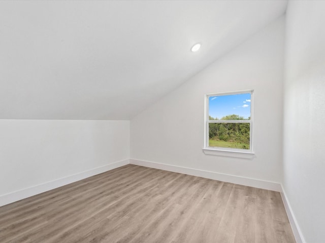 additional living space with recessed lighting, light wood-style floors, baseboards, and vaulted ceiling