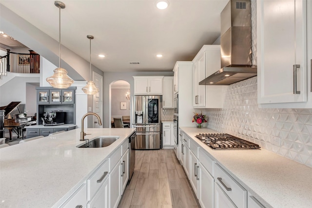 404 Christians Ct, Montgomery, TX 77316 - kitchen featuring stainless steel appliances, wall chimney range hood, visible vents, a sink, and arched walkways