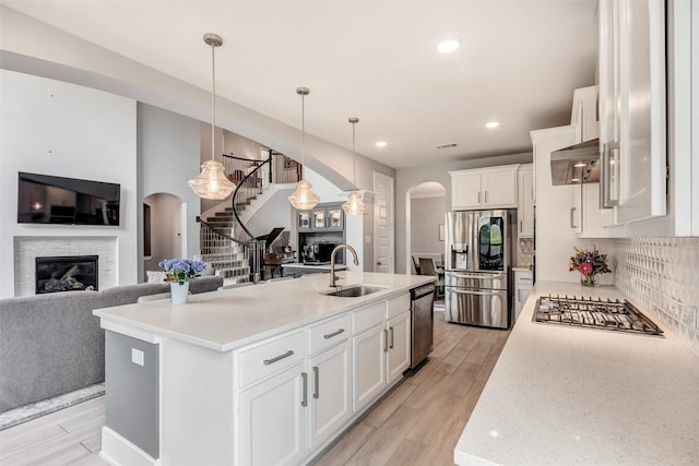404 Christians Ct, Montgomery, TX 77316 - kitchen with a sink, open floor plan, a glass covered fireplace, arched walkways, and appliances with stainless steel finishes