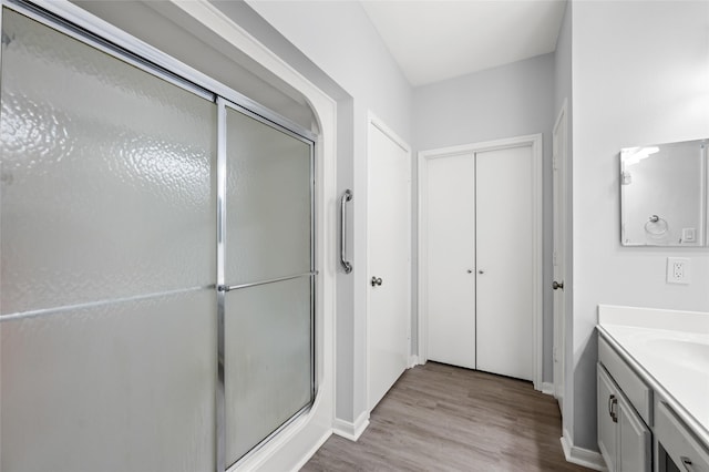 full bath with a shower stall, wood finished floors, vanity, and baseboards
