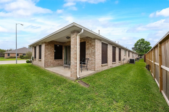 back of house featuring central AC, a patio, a lawn, and brick siding