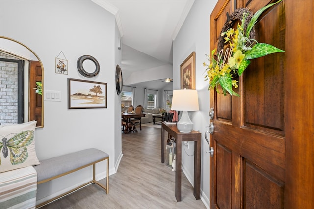 foyer featuring baseboards, ceiling fan, light wood-style floors, crown molding, and lofted ceiling