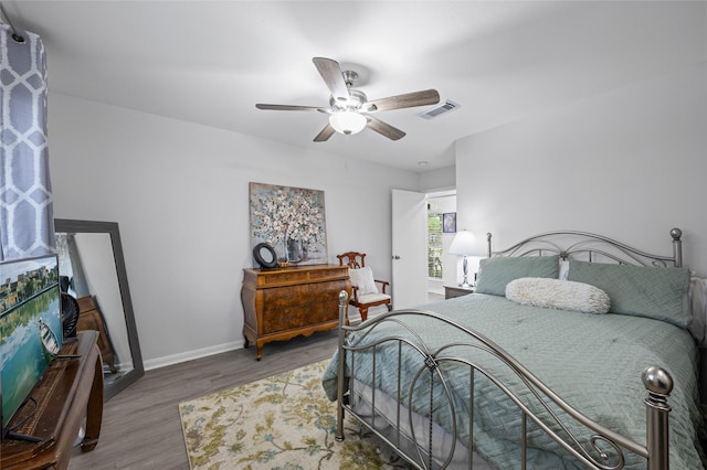 bedroom with wood finished floors, ceiling fan, baseboards, and visible vents