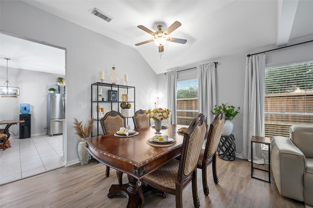 dining room with a ceiling fan, light wood-style floors, vaulted ceiling, and visible vents