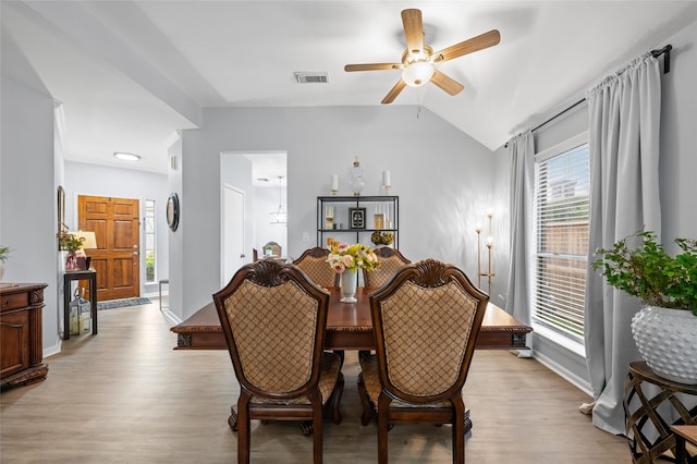 dining space featuring visible vents, baseboards, ceiling fan, vaulted ceiling, and light wood-style flooring