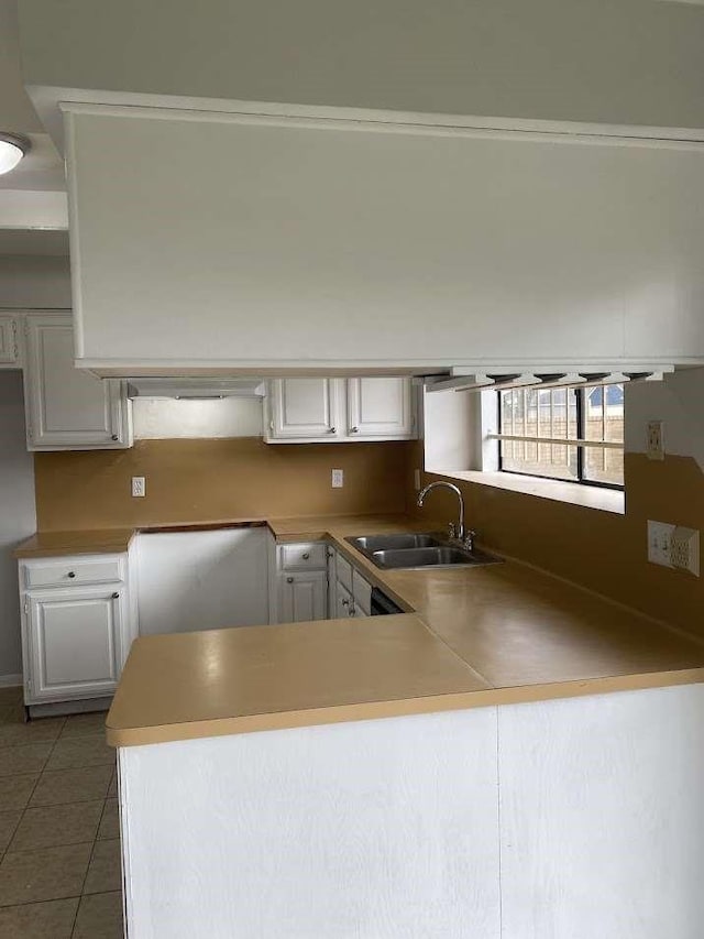 12403 Seaswept Dr, Houston, TX 77071 - kitchen featuring a peninsula, light tile patterned floors, a sink, and white cabinetry