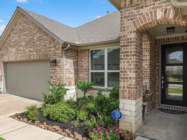 property entrance with concrete driveway, roof with shingles, brick siding, and an attached garage