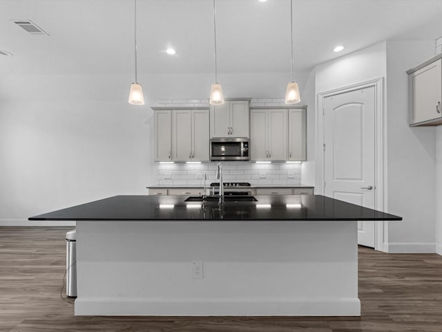 kitchen featuring a sink, visible vents, stainless steel microwave, and dark countertops