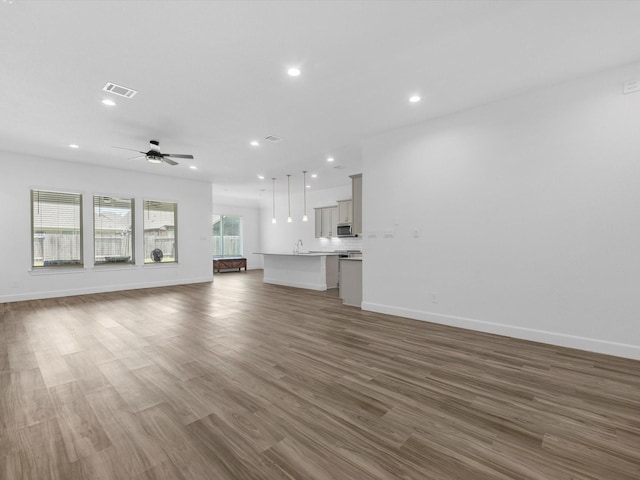 unfurnished living room with baseboards, recessed lighting, visible vents, ceiling fan, and wood finished floors
