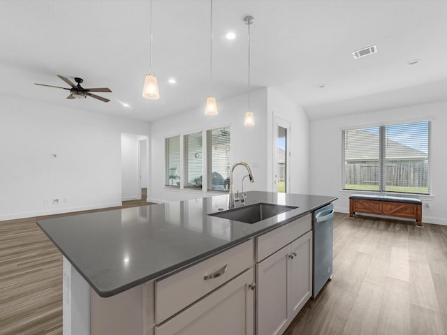 kitchen with open floor plan, dark countertops, dark wood-type flooring, dishwasher, and a sink