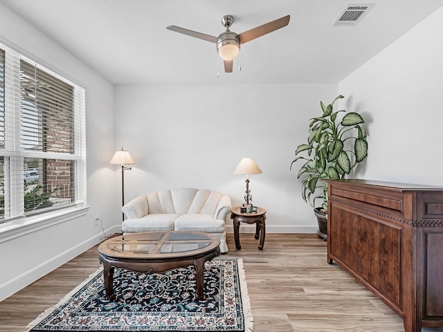 sitting room featuring visible vents, light wood-style flooring, a ceiling fan, and baseboards