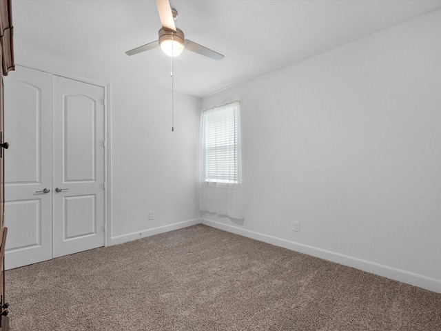 carpeted spare room with baseboards and a ceiling fan