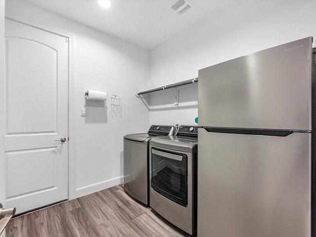 laundry area featuring visible vents, baseboards, laundry area, wood finished floors, and washing machine and dryer