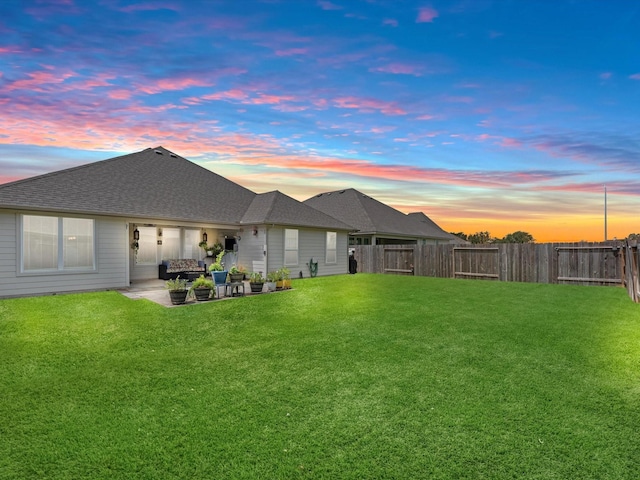 rear view of house with a patio area, a shingled roof, fence, and a lawn