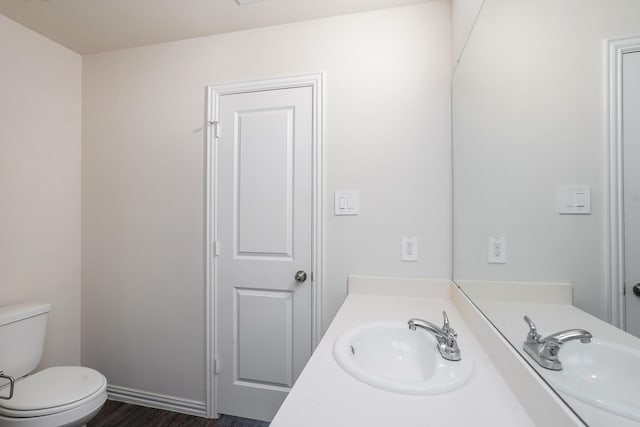 bathroom with vanity, toilet, and wood finished floors