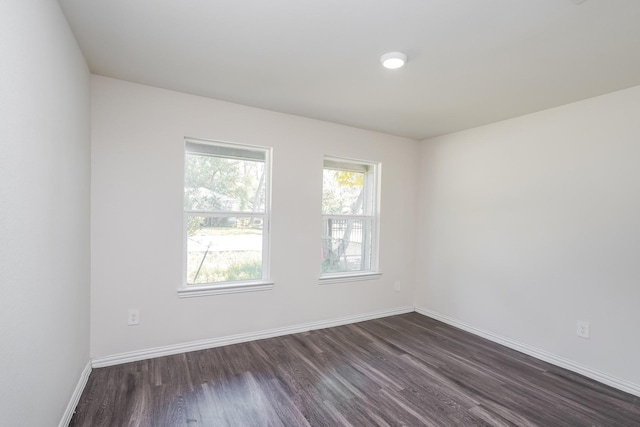 spare room featuring baseboards and dark wood-style floors