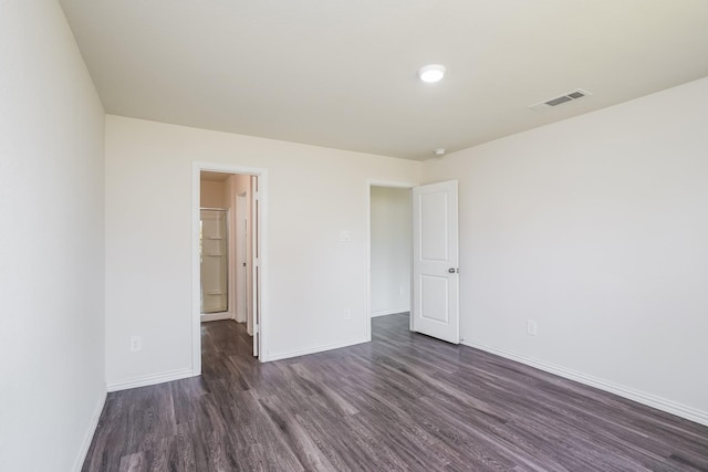 empty room featuring baseboards, dark wood-style floors, and visible vents