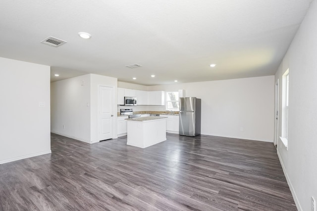 unfurnished living room featuring dark wood-style flooring, visible vents, baseboards, and recessed lighting