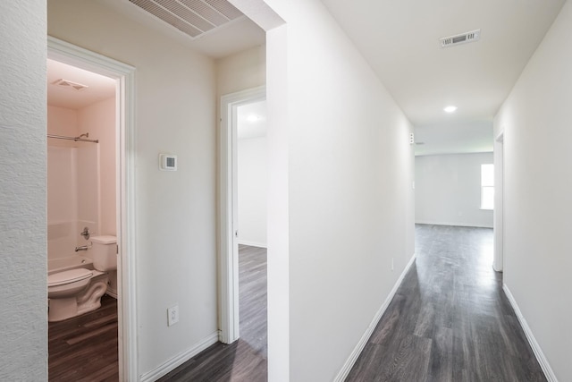 hallway featuring dark wood-type flooring and visible vents