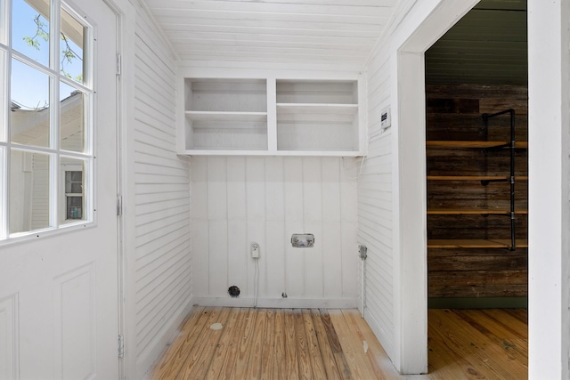 laundry room featuring light wood-style flooring and wooden walls