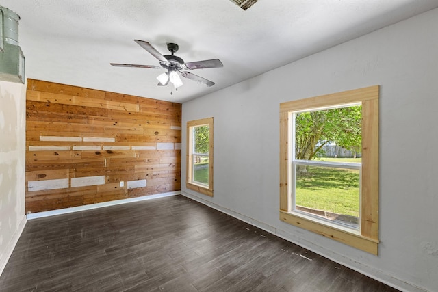 empty room with wood finished floors, ceiling fan, baseboards, and wooden walls