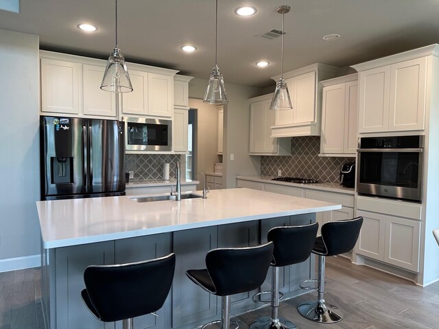 kitchen with tasteful backsplash, recessed lighting, visible vents, stainless steel appliances, and a sink