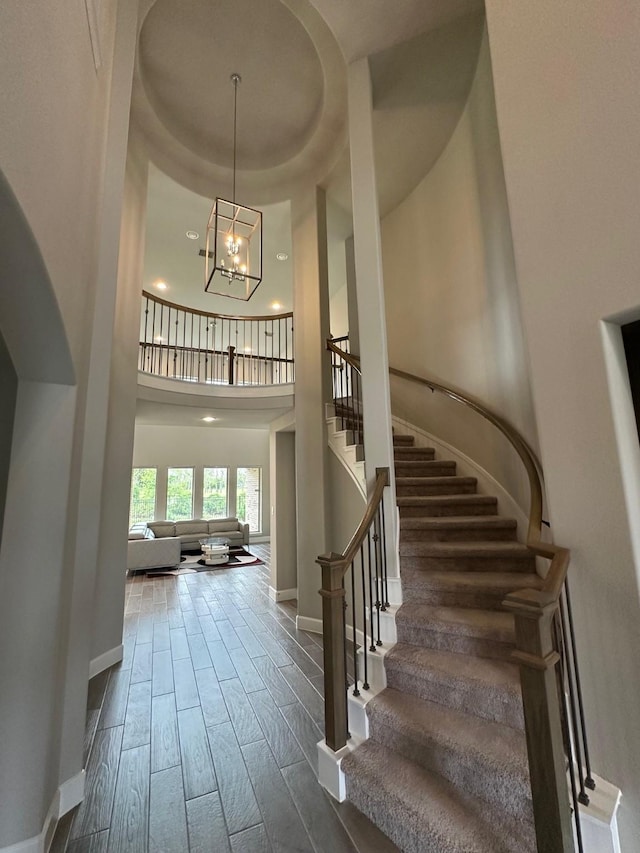 entrance foyer with a notable chandelier, baseboards, stairway, a high ceiling, and wood finished floors