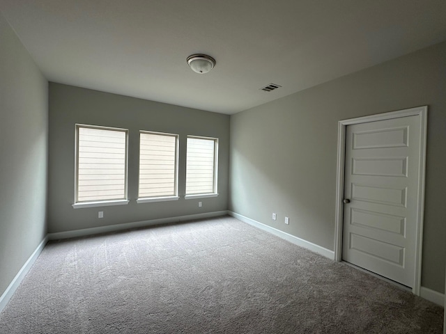carpeted spare room with visible vents and baseboards