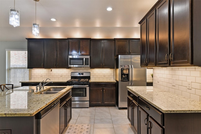 kitchen with a sink, tasteful backsplash, pendant lighting, light stone counters, and appliances with stainless steel finishes