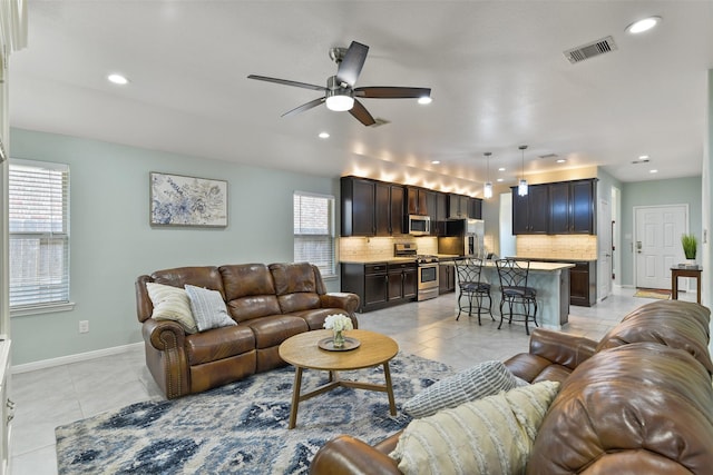 living area featuring light tile patterned floors, ceiling fan, baseboards, visible vents, and recessed lighting
