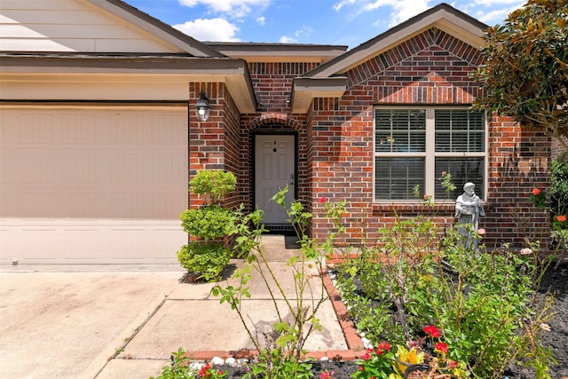 entrance to property featuring an attached garage, driveway, and brick siding