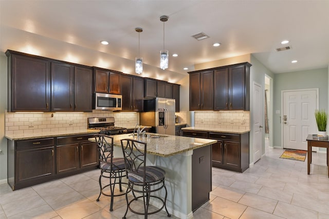 kitchen featuring a breakfast bar, light stone countertops, stainless steel appliances, and visible vents