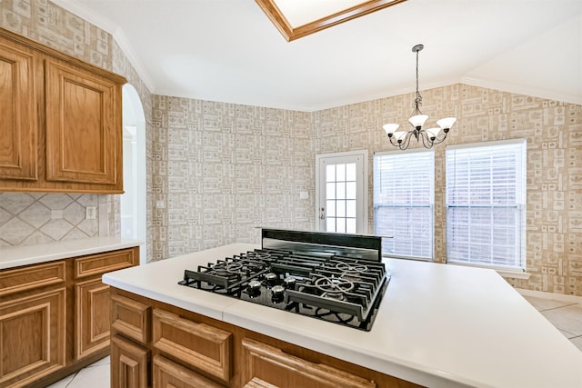 kitchen featuring brown cabinets, light tile patterned flooring, light countertops, a notable chandelier, and black gas cooktop