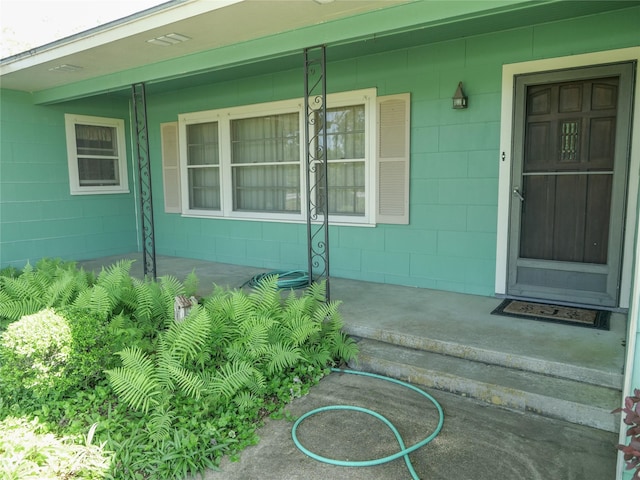 entrance to property featuring covered porch and concrete block siding