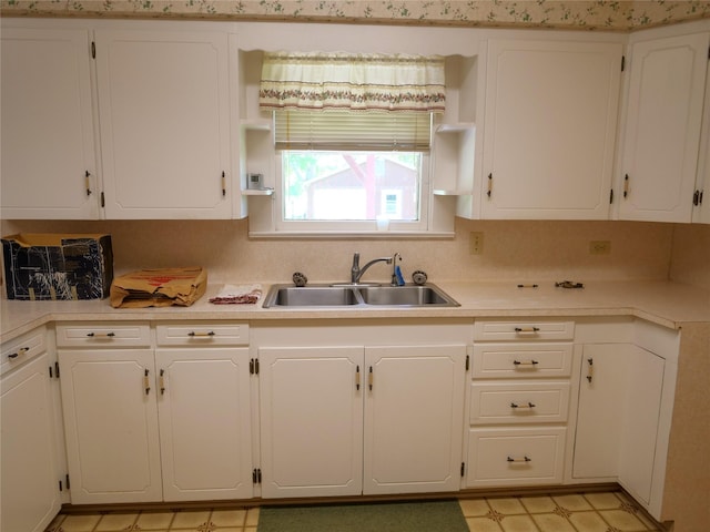 kitchen with light countertops, white cabinetry, a sink, and light floors