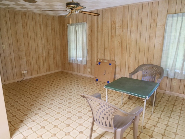 sitting room with wood walls, tile patterned floors, baseboards, and a ceiling fan