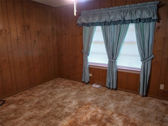 carpeted empty room featuring wooden walls