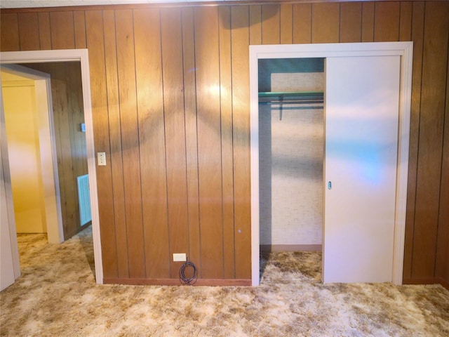 unfurnished bedroom with wood walls, visible vents, a closet, and carpet floors