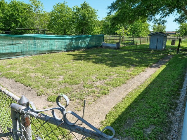 view of yard with an outdoor structure, fence, and a storage unit