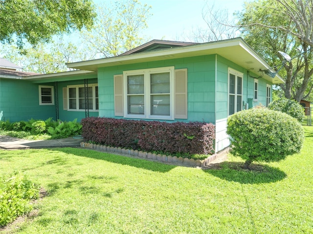 view of side of home featuring a yard and concrete block siding
