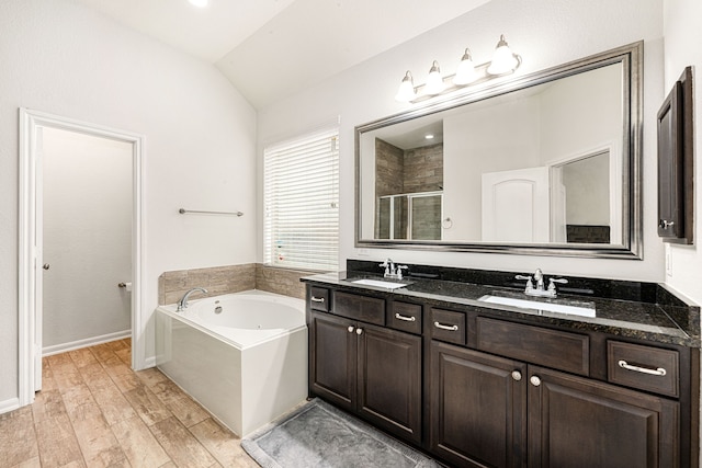 full bathroom with a shower stall, double vanity, a sink, and lofted ceiling