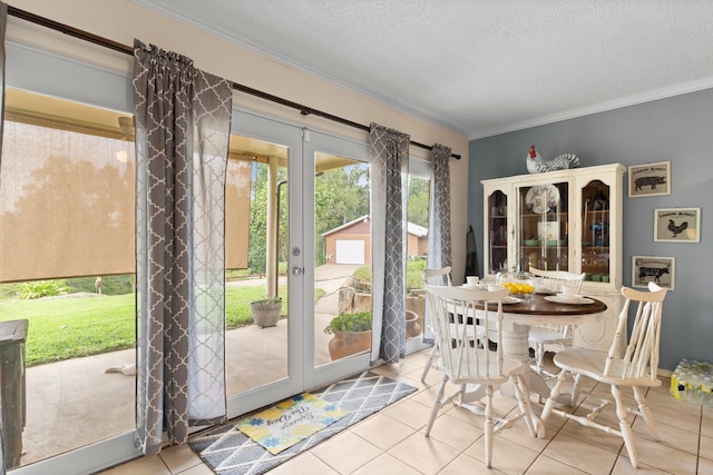 tiled dining room with french doors, a textured ceiling, and crown molding