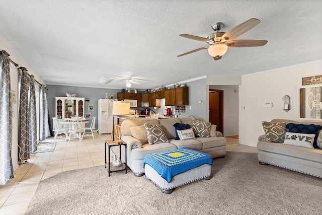 living area with ornamental molding, light tile patterned floors, a ceiling fan, and a textured ceiling