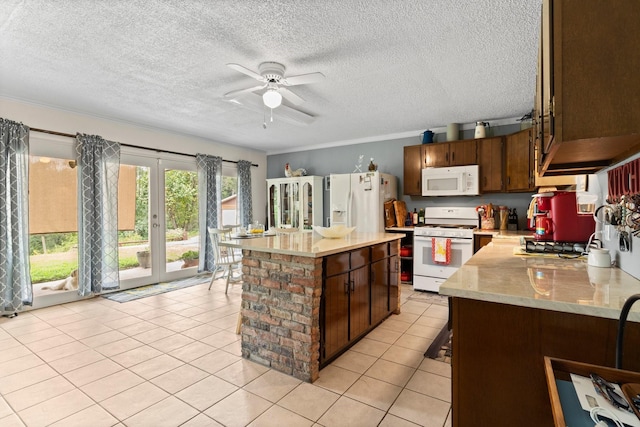 kitchen with light tile patterned floors, a center island, a ceiling fan, white appliances, and a textured ceiling