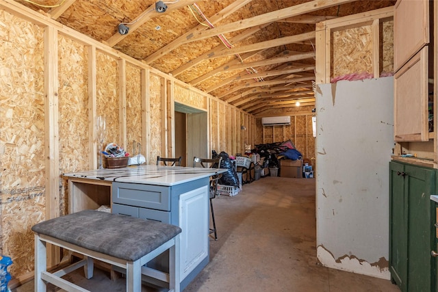 interior space featuring concrete floors, vaulted ceiling, and a wall unit AC