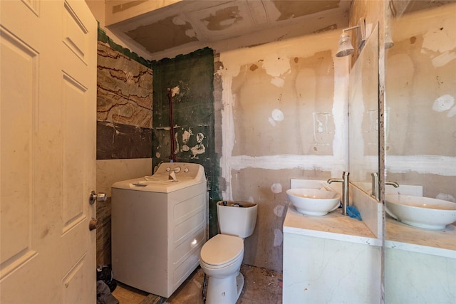 bathroom with washer / clothes dryer, double vanity, a sink, and toilet