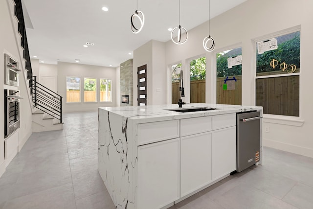 kitchen featuring a sink, stainless steel appliances, light stone countertops, recessed lighting, and a center island with sink